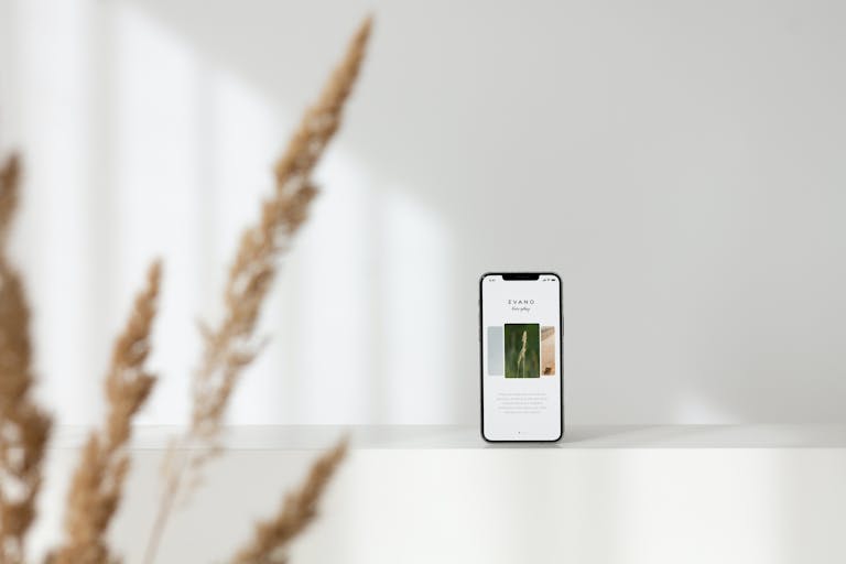 A sleek smartphone displaying content, set against a minimalist white background with blurred foreground elements.
