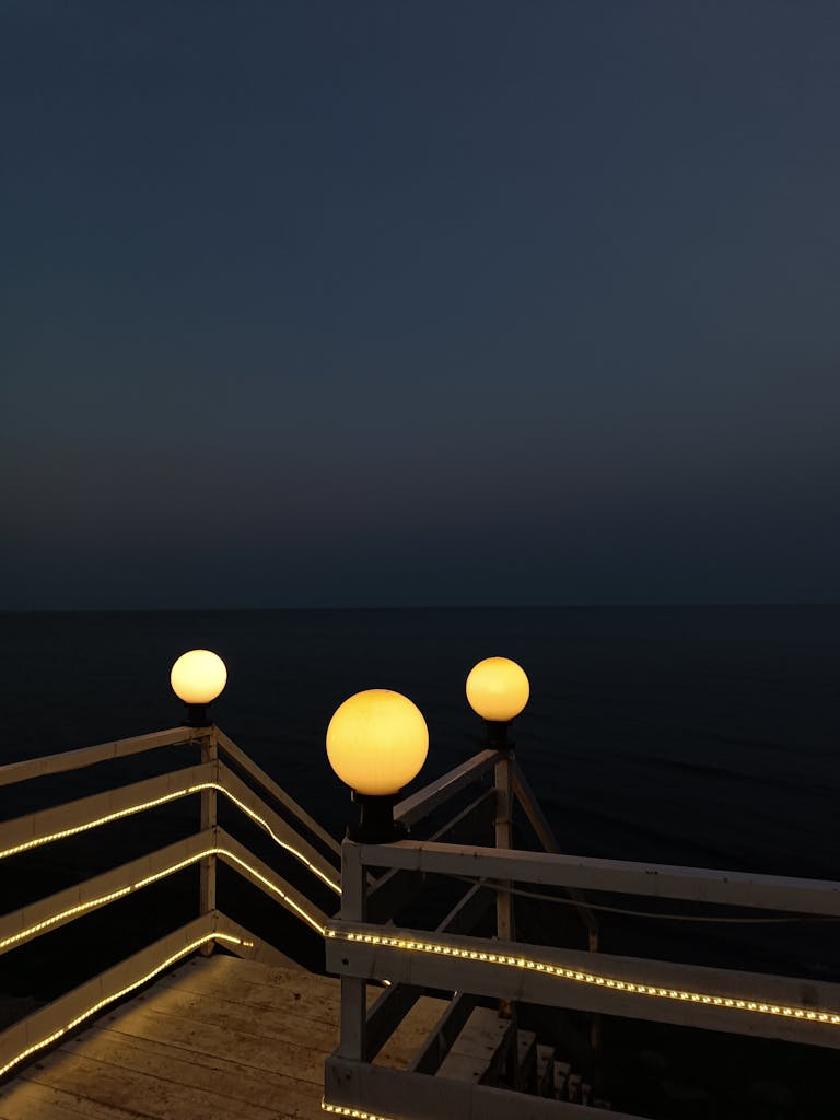 Captivating twilight scene of an illuminated seaside stairway leading towards the dark ocean.