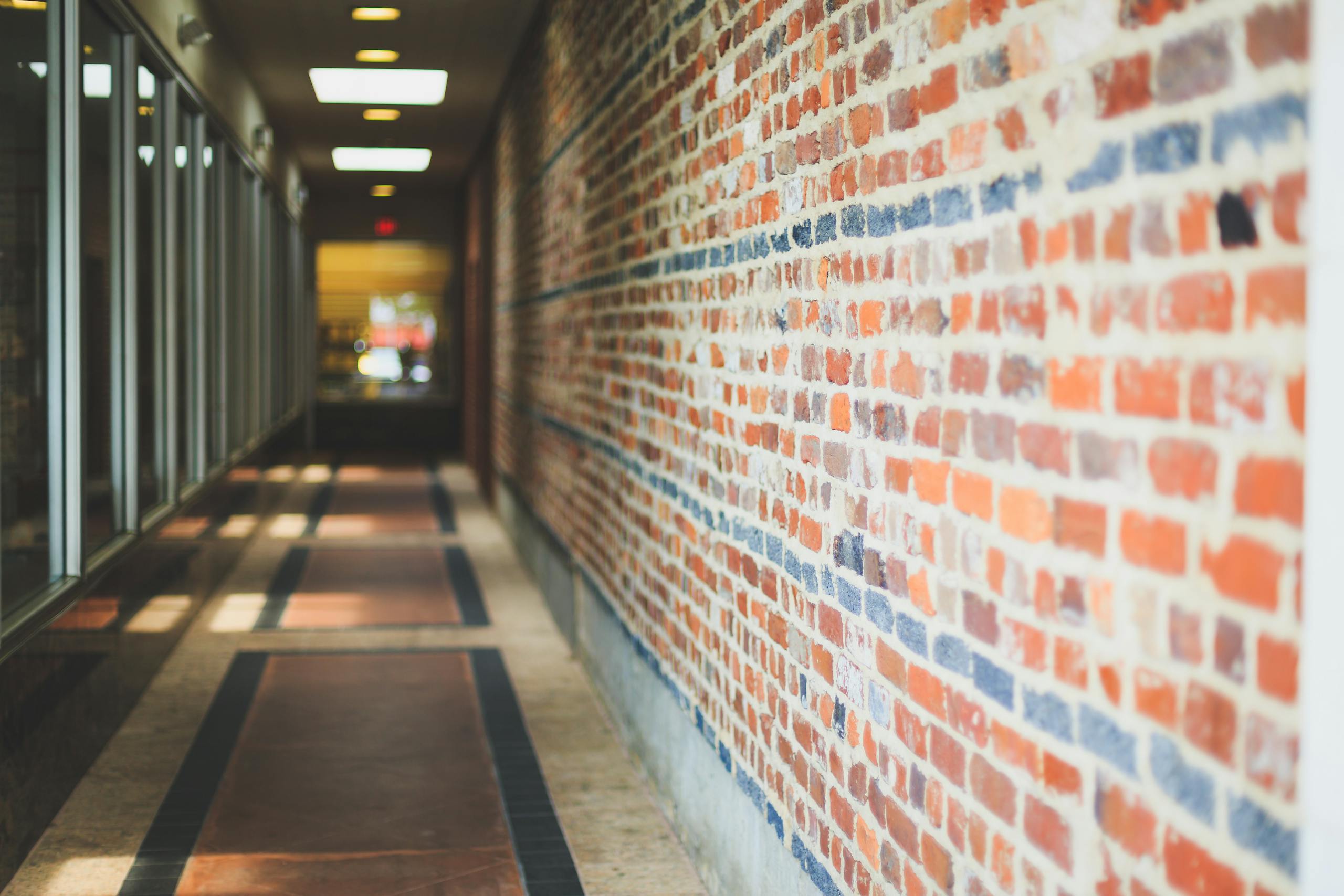 Modern corridor with brick walls and glass facade creating a perspective view.